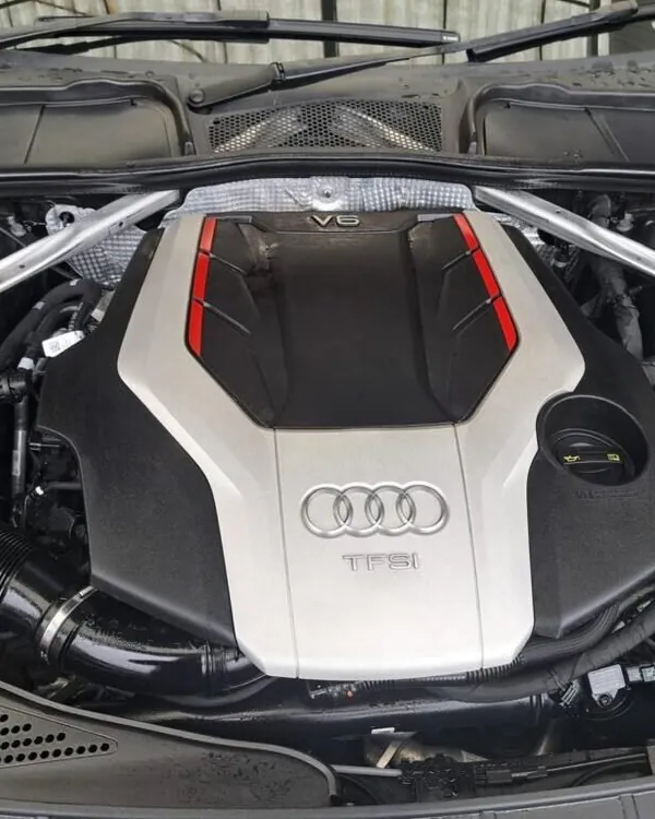 Engine bay of an Audi with a V6 TFSI engine, the bonnet raised and the silver engine cover in place
