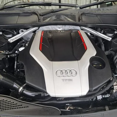 Engine bay of an Audi with a V6 TFSI engine, the bonnet raised and the silver engine cover in place