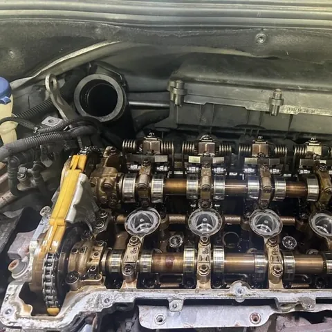 Top of a four-cylinder engine with the cam cover removed, showing twin camshafts, valve gear and the timing chain