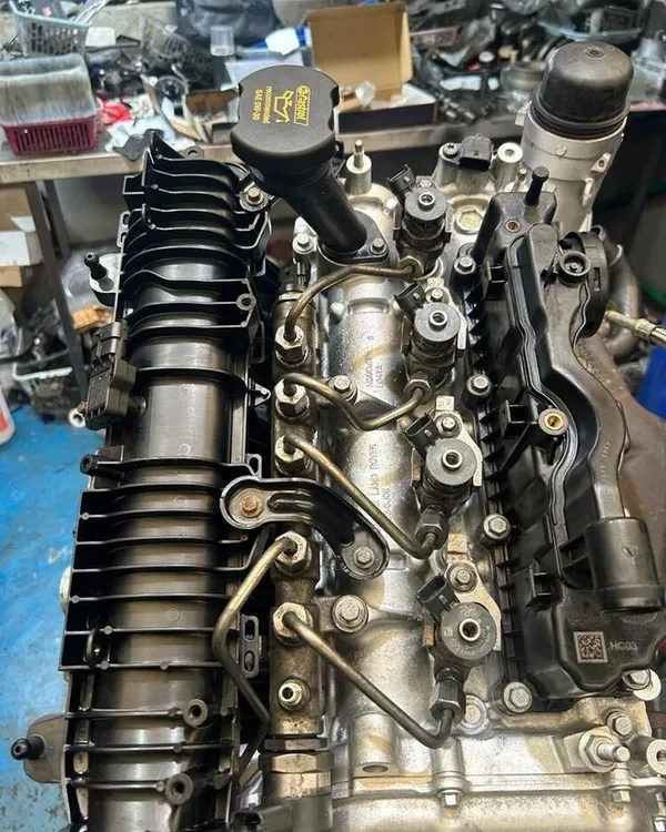Top of a diesel engine on a workshop stand, showing the injectors, high-pressure fuel pipes and inlet manifold