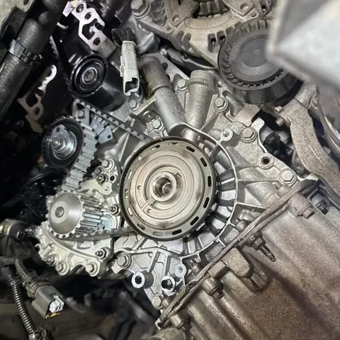 Front of an engine with the timing covers removed, showing the toothed timing belt, sprockets and tensioner